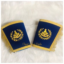 Load image into Gallery viewer, Blue Past Master Masonic Cuffs. Blue velvet. Gold bullion and braided edges and fringe. Embroidered masonic symbol. Design outlined in 100% Swarovski Crystals.
